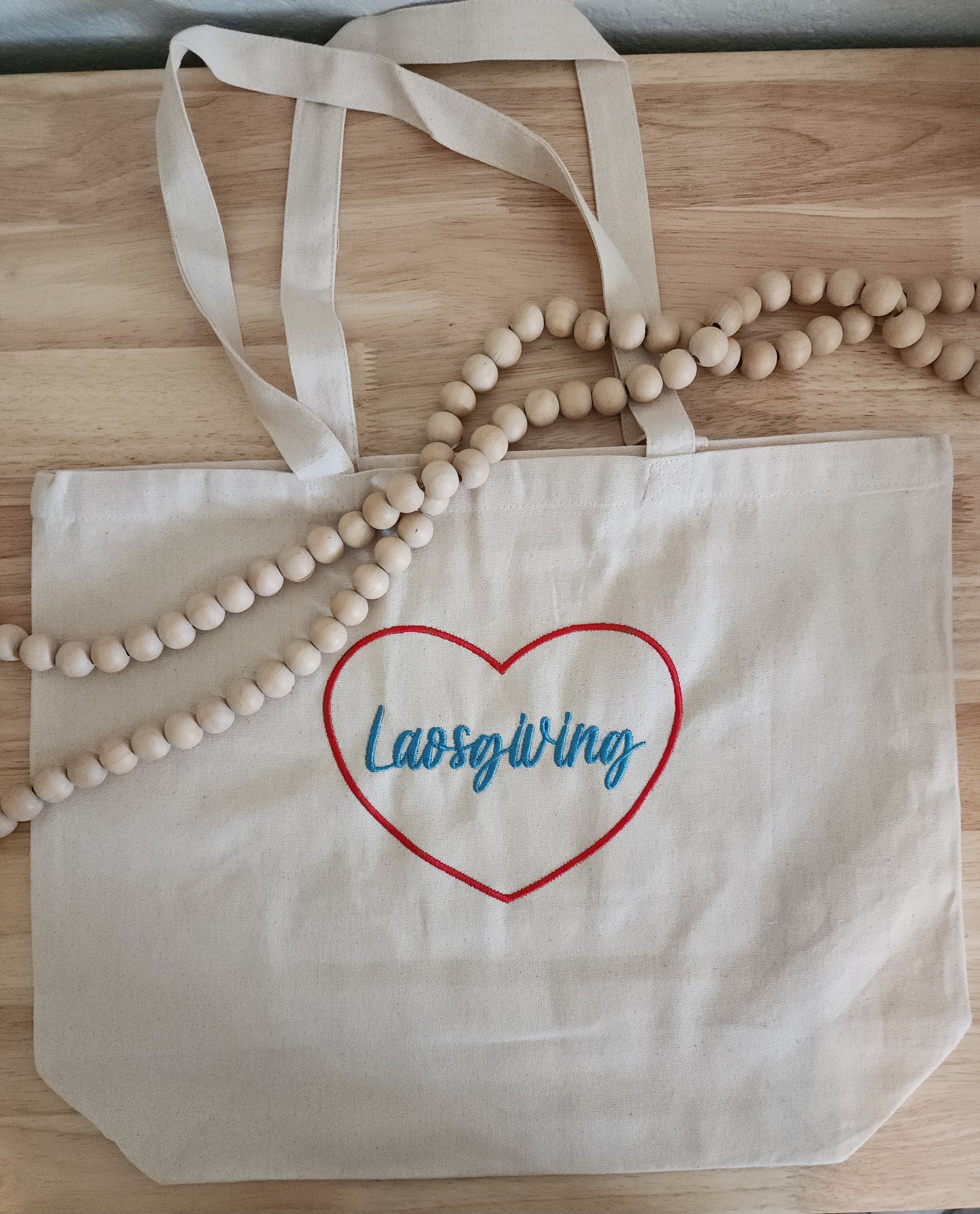 Beige tote bag with custom text and design, like "Laosgiving."